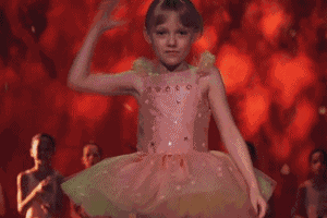 a girl in a pink dress with a green hat is dancing