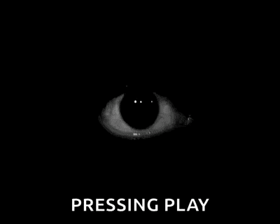 a close up of a person 's eye in the dark with the words `` pressing play '' written below it .