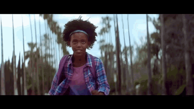 a young girl with a backpack is running through a forest