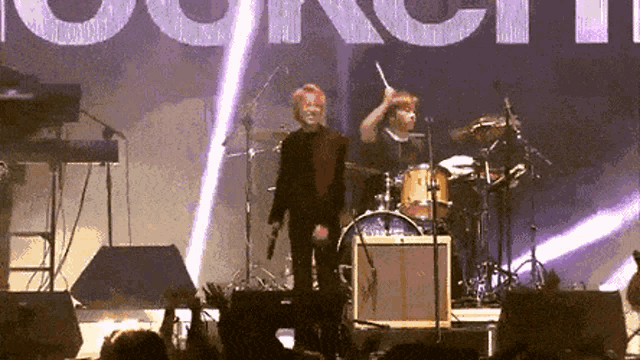 a man stands on a stage with a drum stick in front of a sign that says " council "