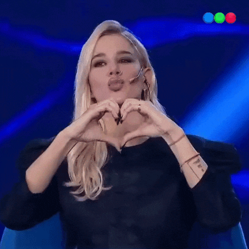 a woman making a heart shape with her hands while wearing a microphone