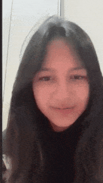 a girl with long black hair is smiling and looking at the camera