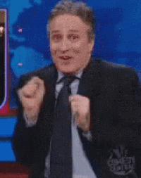 a man in a suit and tie is clapping in front of a comedy central sign
