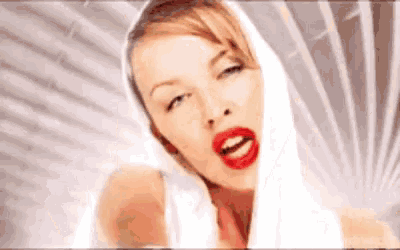 a woman with red lipstick and a white scarf around her head is smiling .