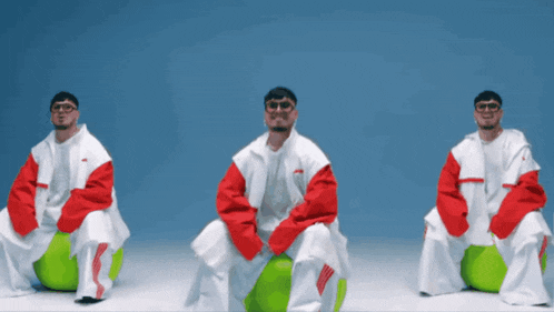 three men are sitting on green balls wearing white and red jackets