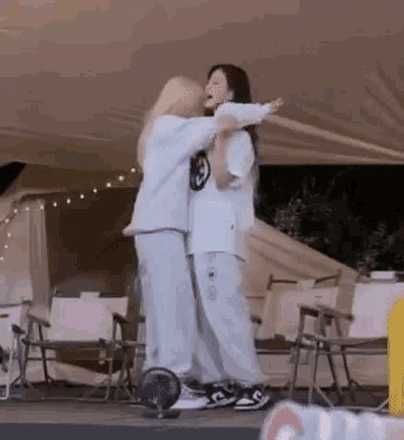 a couple of women hugging each other in front of a tent .