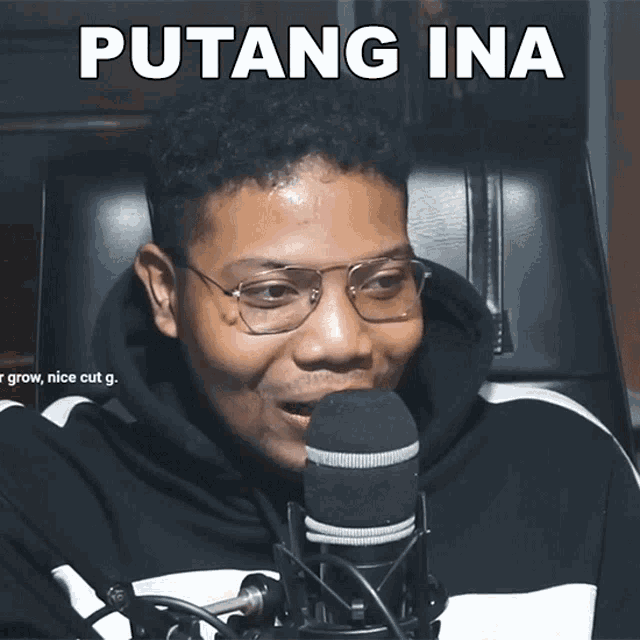 a man wearing glasses is sitting in front of a microphone with the words putang ina written above him