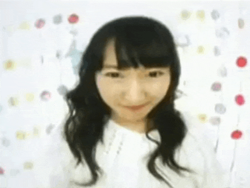 a woman in a white shirt is smiling in front of a white background with flowers .