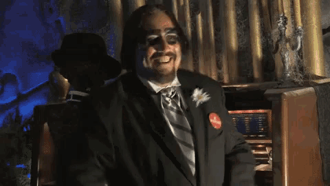 a man in a tuxedo is clapping his hands in front of a statue