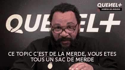 a man with a beard and glasses is sitting in front of a sign that says quemel +