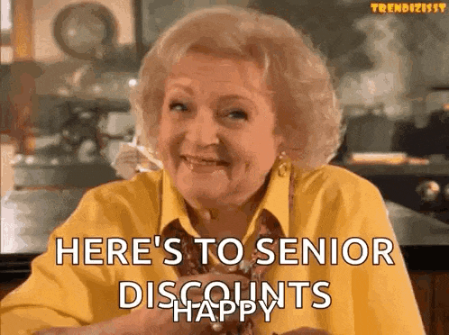 an elderly woman in a yellow shirt is smiling and saying `` here 's to senior discounts happy ''