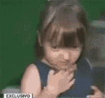 a little girl in a blue dress is covering her face with her hands ..