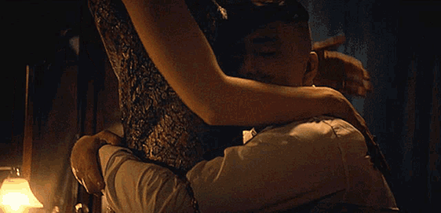 a man and a woman are hugging each other in a dark room