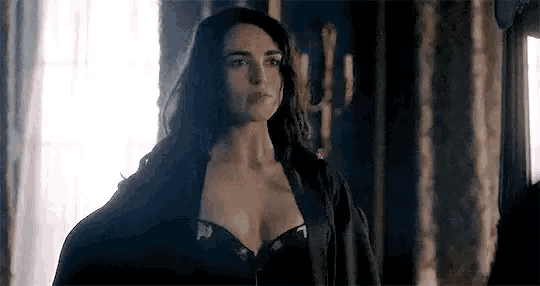 a woman in a black bra is standing in a room looking at the camera .