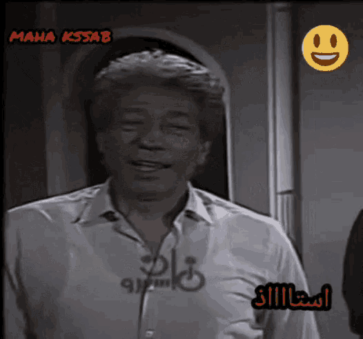 a man in a white shirt is smiling in front of a smiley face that says maha kssab on it
