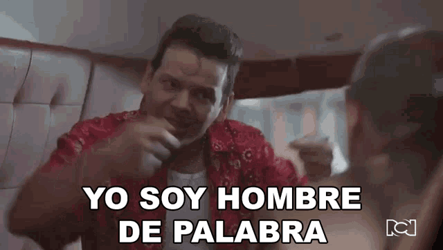 a man in a red shirt is talking to another man and says yo soy hombre de palabra