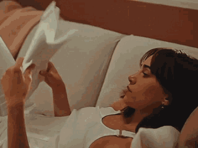 a woman is sitting on a couch reading a book .
