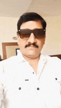 a man wearing sunglasses and a white shirt is taking a picture of himself