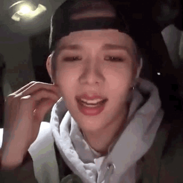 a close up of a person wearing a hat and a white hoodie