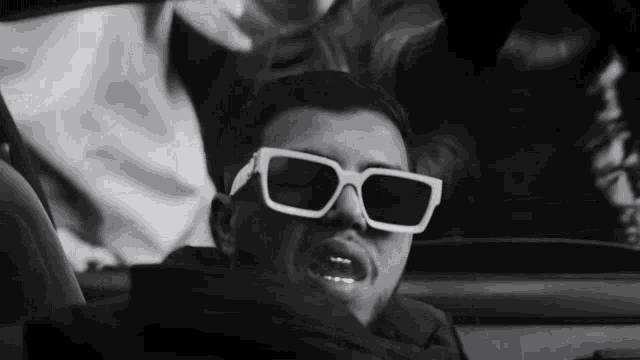 a man wearing white sunglasses is sitting in a car