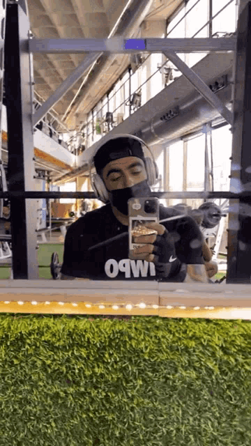 a man wearing a mask and headphones takes a picture of himself in a gym
