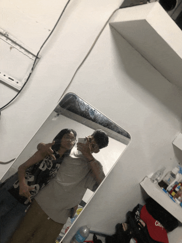 a man and woman are taking a picture in a mirror