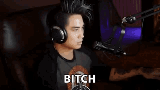 a man wearing headphones is sitting in front of a microphone and says bitch .