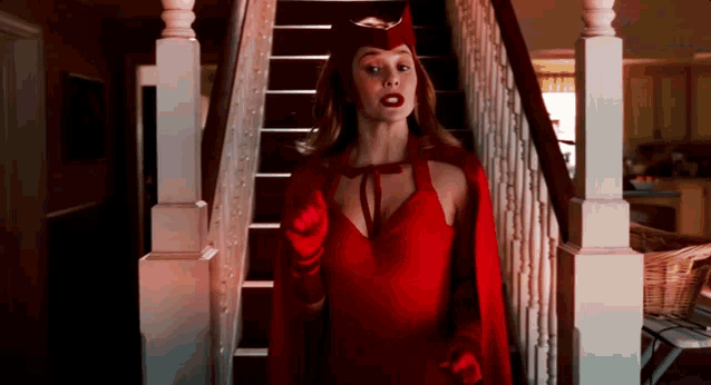 a woman in a red cape and gloves is standing on a set of stairs .