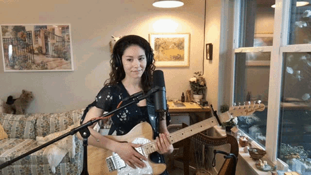 a woman plays a guitar in front of a microphone