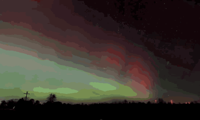 the aurora borealis is visible in the night sky above a cross