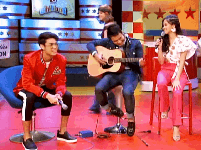 a man in a red jacket with the letter l on it playing a guitar