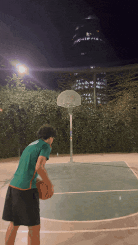 a man in a green shirt is playing basketball in front of a basketball hoop