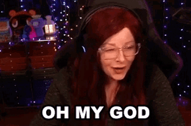 a woman with red hair and glasses is wearing headphones and making a funny face .