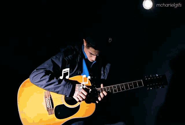 a man playing an acoustic guitar with a light behind him and the words mcharielgifs on the bottom