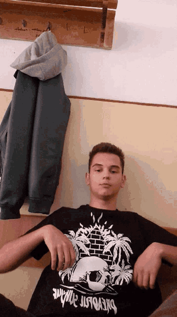 a young man wearing a black t-shirt with a skull and palm trees has his hands on his hips