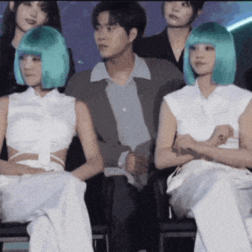 a group of people are sitting in chairs and one of them has a green wig on