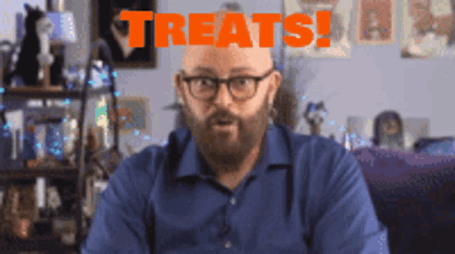 a bald man with glasses and a beard is sitting in front of a sign that says treats
