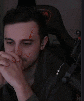 a man wearing headphones is sitting in a chair with his hands folded