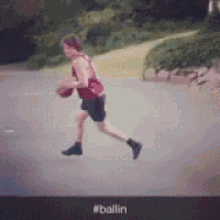 a man in a red tank top is dribbling a basketball down a street .