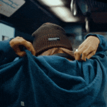 a person wearing a beanie and a sweatshirt with the word crew on the back