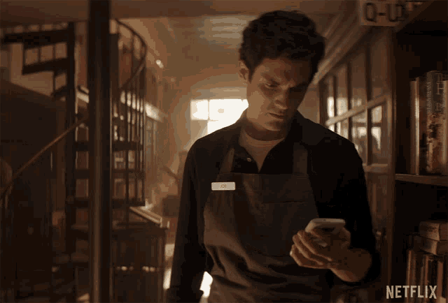 a man in an apron is looking at his phone with netflix written on the bottom right