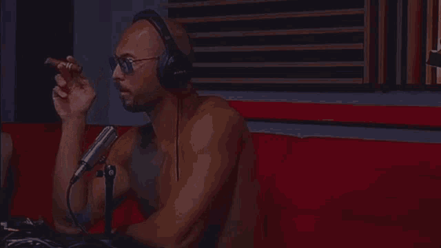 a man wearing headphones is smoking a cigar in front of a microphone