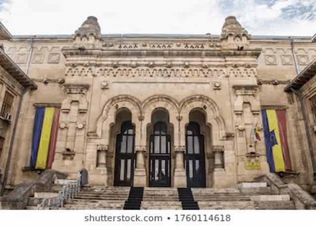 a large building with stairs leading up to it and flags on the side .