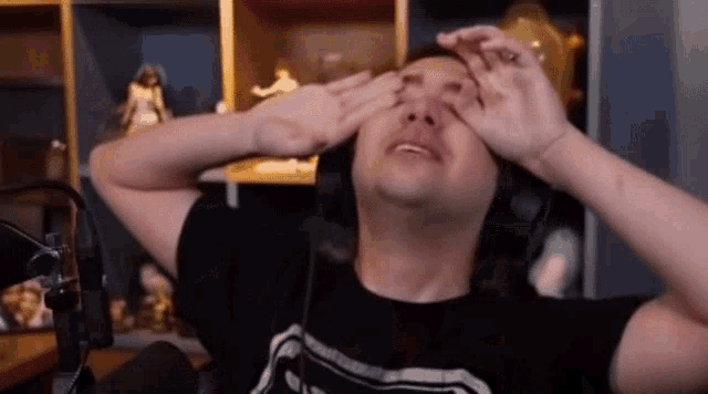 a man wearing headphones is rubbing his eyes .