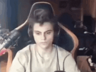 a young man is sitting in a gaming chair wearing headphones and a microphone .