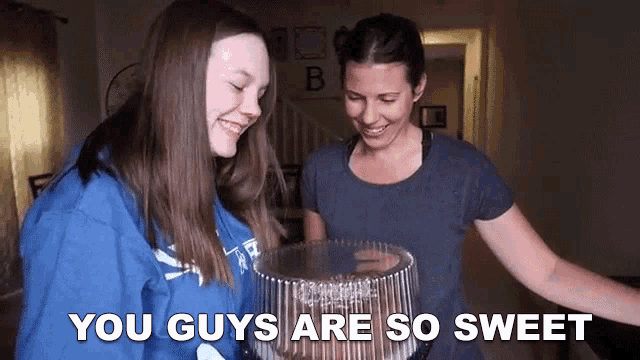 two women standing next to each other holding a cake with the words " you guys are so sweet " on the bottom