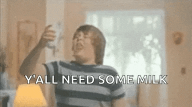 a boy is sitting on a couch holding a bottle of milk and screaming .