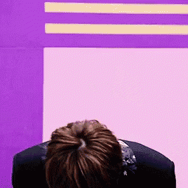 a person is sitting in front of a pink and purple wall .