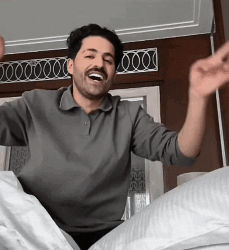 a man in a grey shirt is laying on a bed