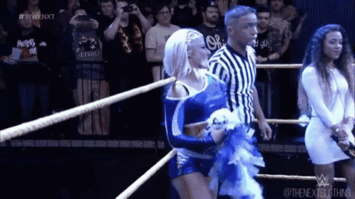 a couple of women are standing in a wrestling ring .